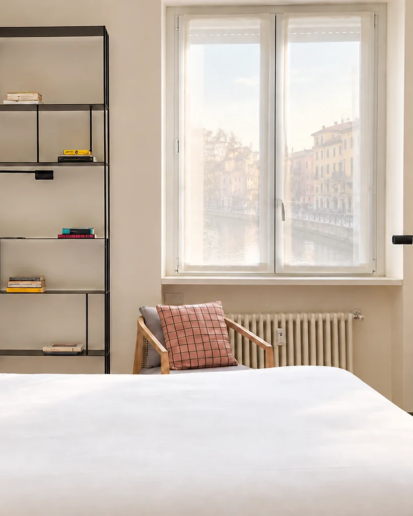 Camera con letto matrimoniale, una libreria in metallo e la finestra sul canale: Casa Navigli, Milano