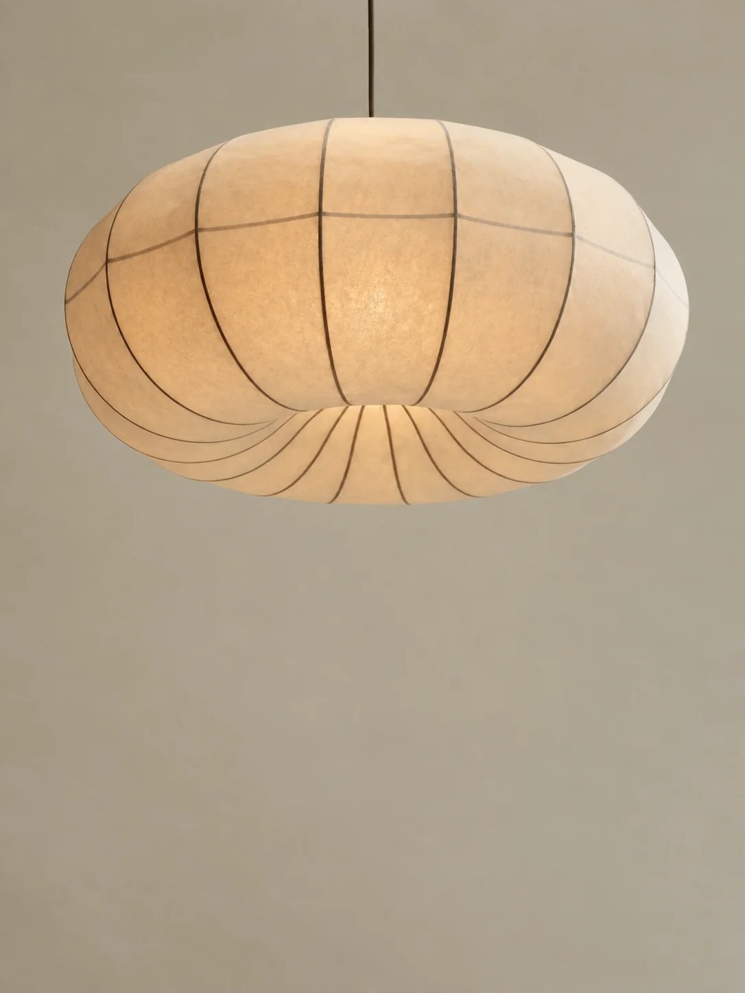 A cocoon pendant lamp, pale fabric stretched over a slender frame
