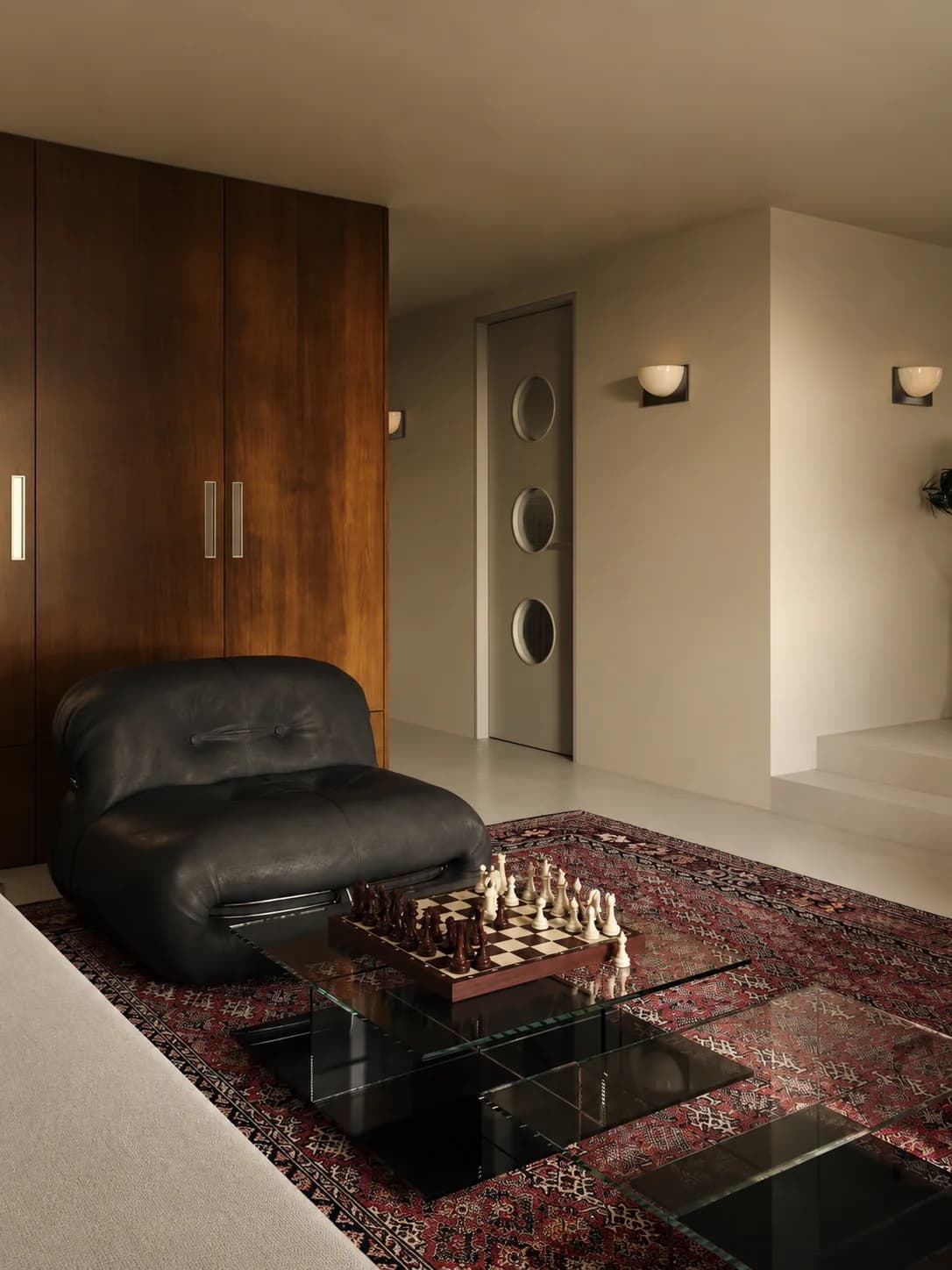 A sitting room with dark leather armchairs, a chess table and a Persian rug