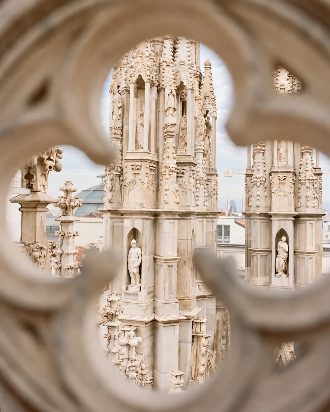 Le guglie del Duomo di Milano viste attraverso il traforo di una balaustra di marmo