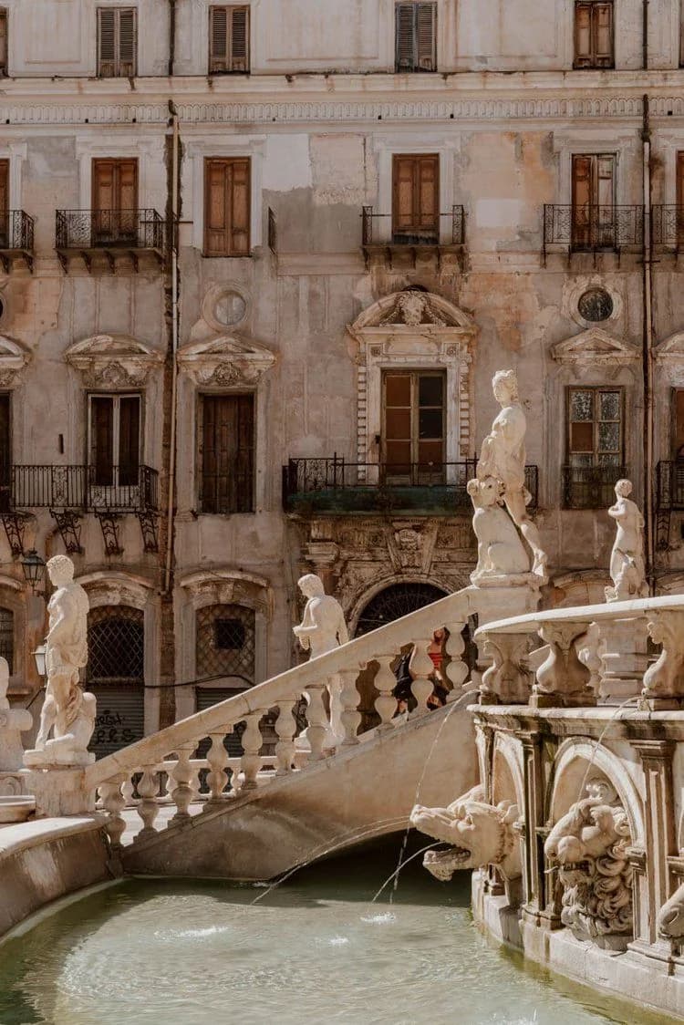 Le statue e la balaustra della Fontana Pretoria, davanti a un palazzo barocco di Palermo