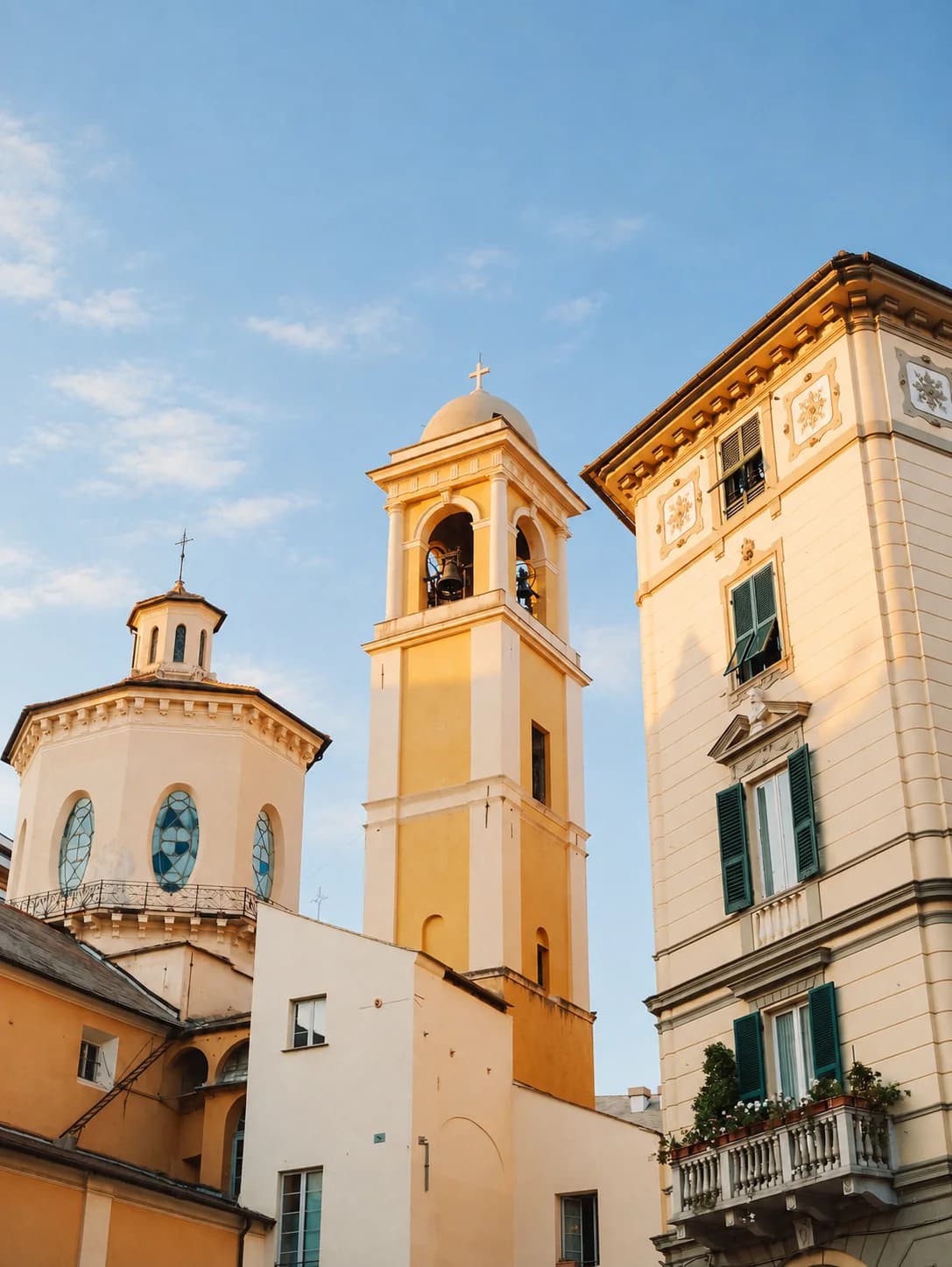 Il campanile giallo di una chiesa fra i palazzi pastello del centro, contro il cielo