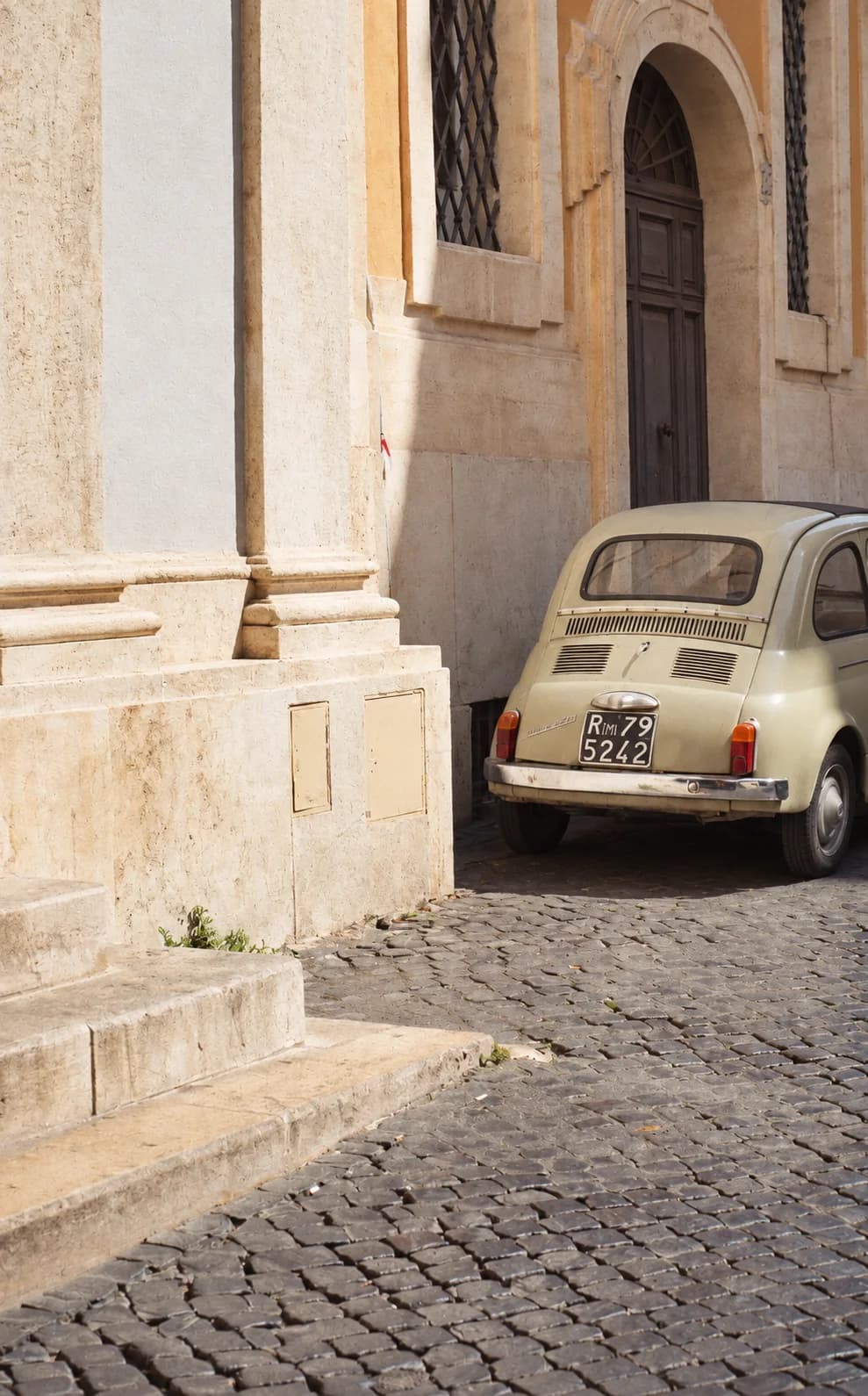 Una Fiat 500 parcheggiata su una via di ciottoli, accanto al portale di una chiesa torinese