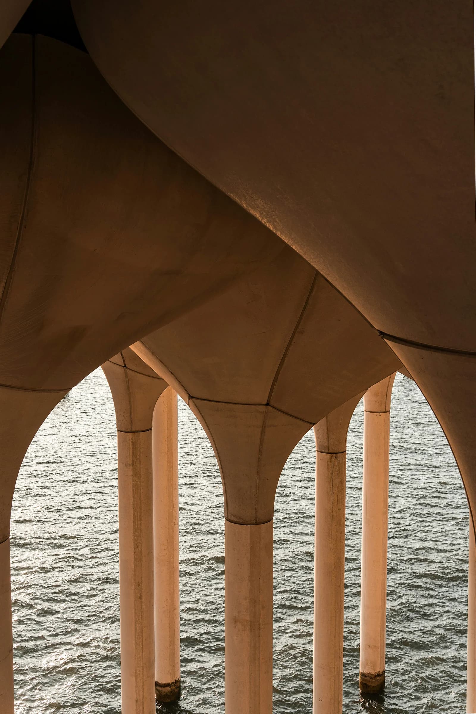 Un porticato ad archi con una tenda tesa sopra, aperto sulla luce del giorno