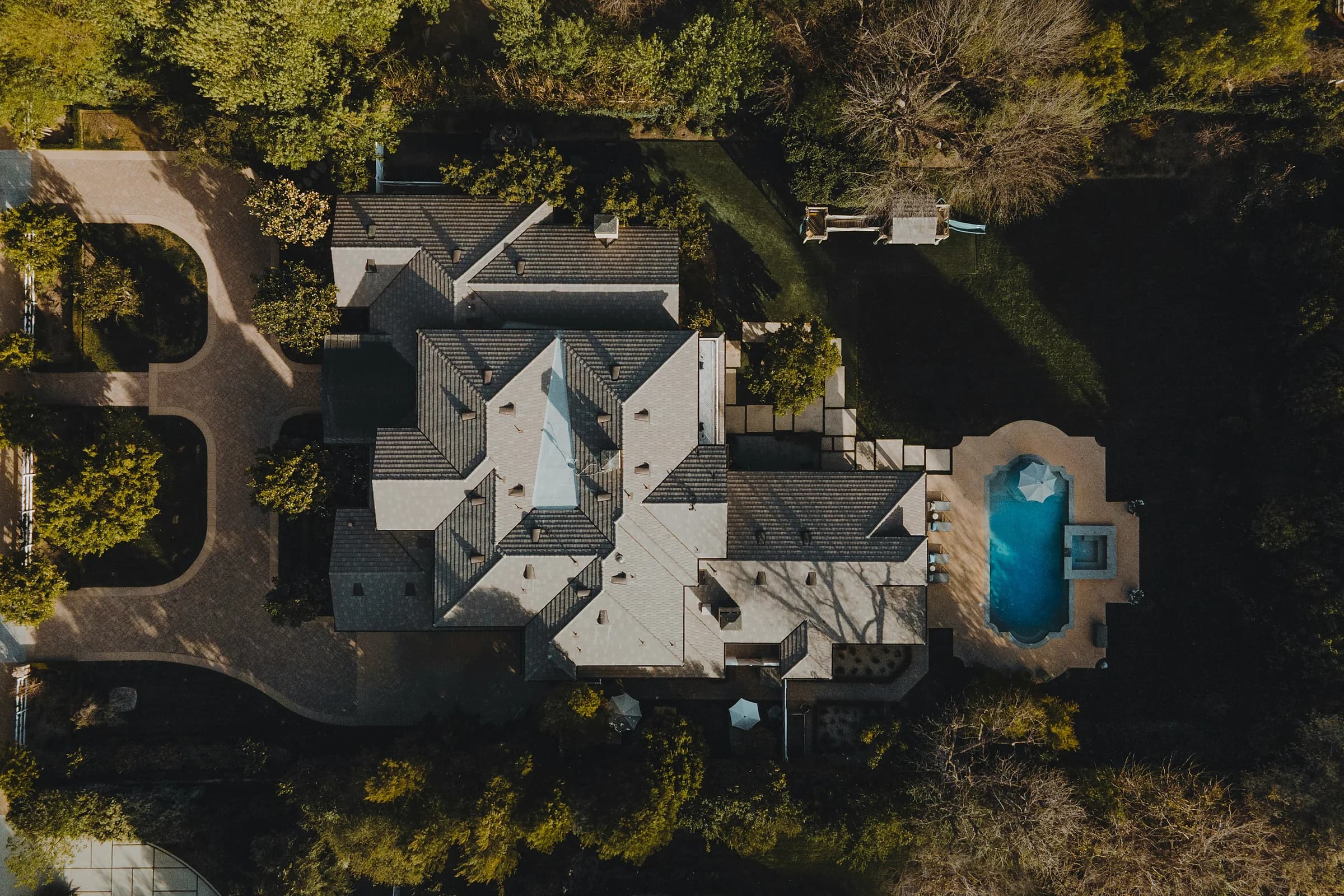 Una villa vista dall’alto, col giardino, gli alberi e la piscina azzurra