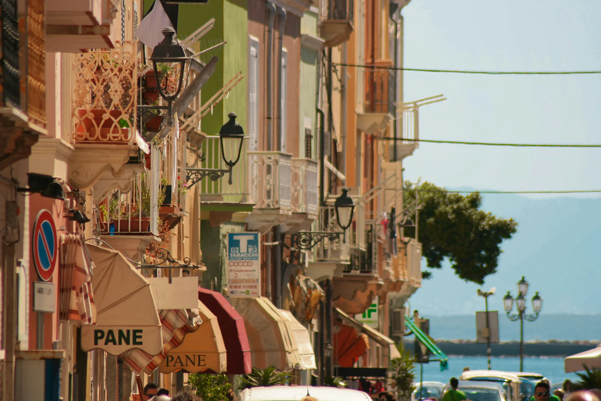 Una via in discesa verso il mare, con le tende dei negozi e le case colorate