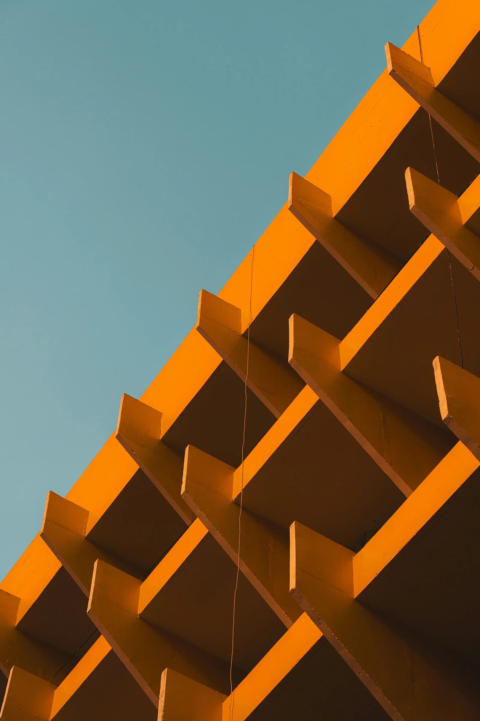 La facciata arancione di un edificio, con una griglia di aggetti geometrici contro il cielo azzurro