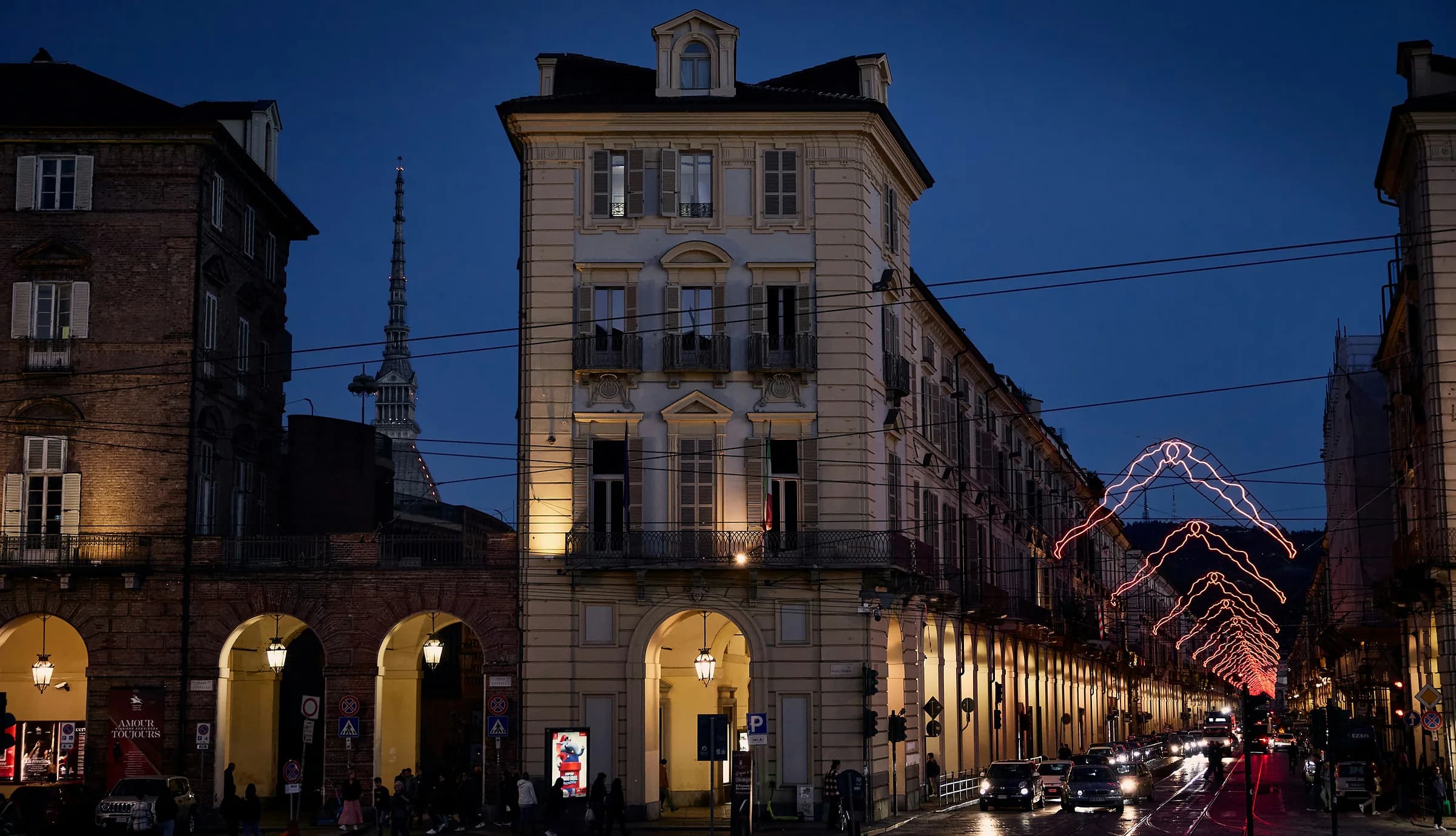 Una via di Torino al crepuscolo, con le luci di Natale sotto i portici e la Mole in fondo