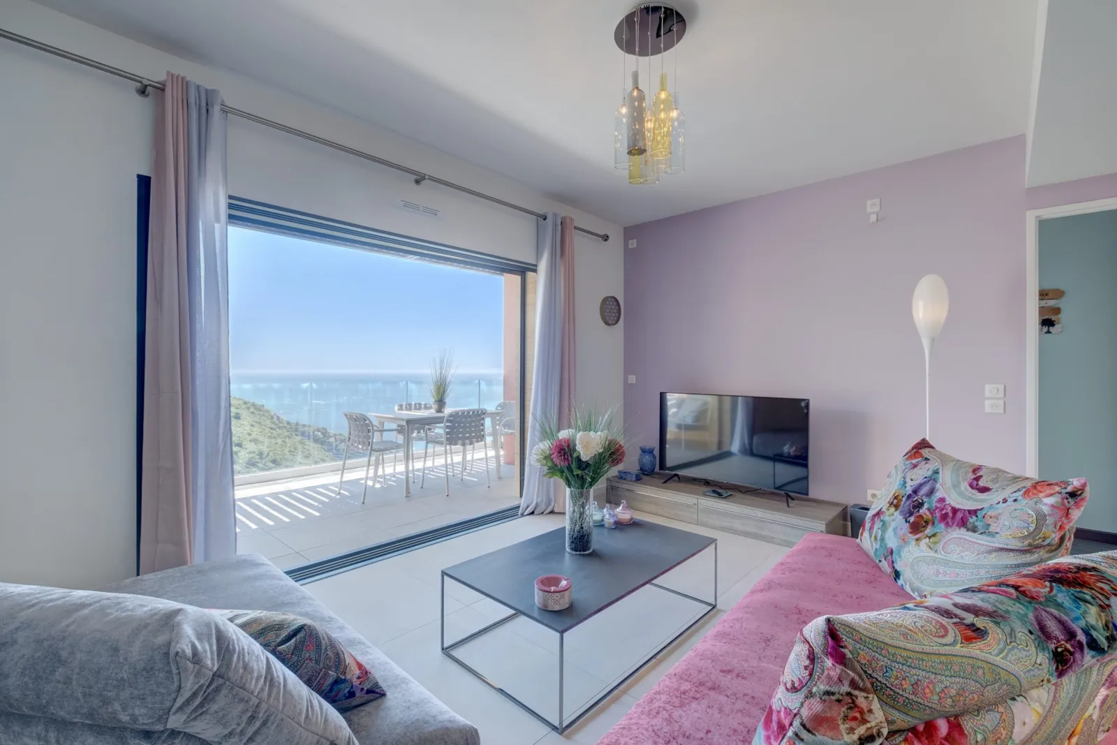 Il soggiorno di Divino Luxe Apartment: un divano con cuscini colorati e la vetrata sulla terrazza vista mare