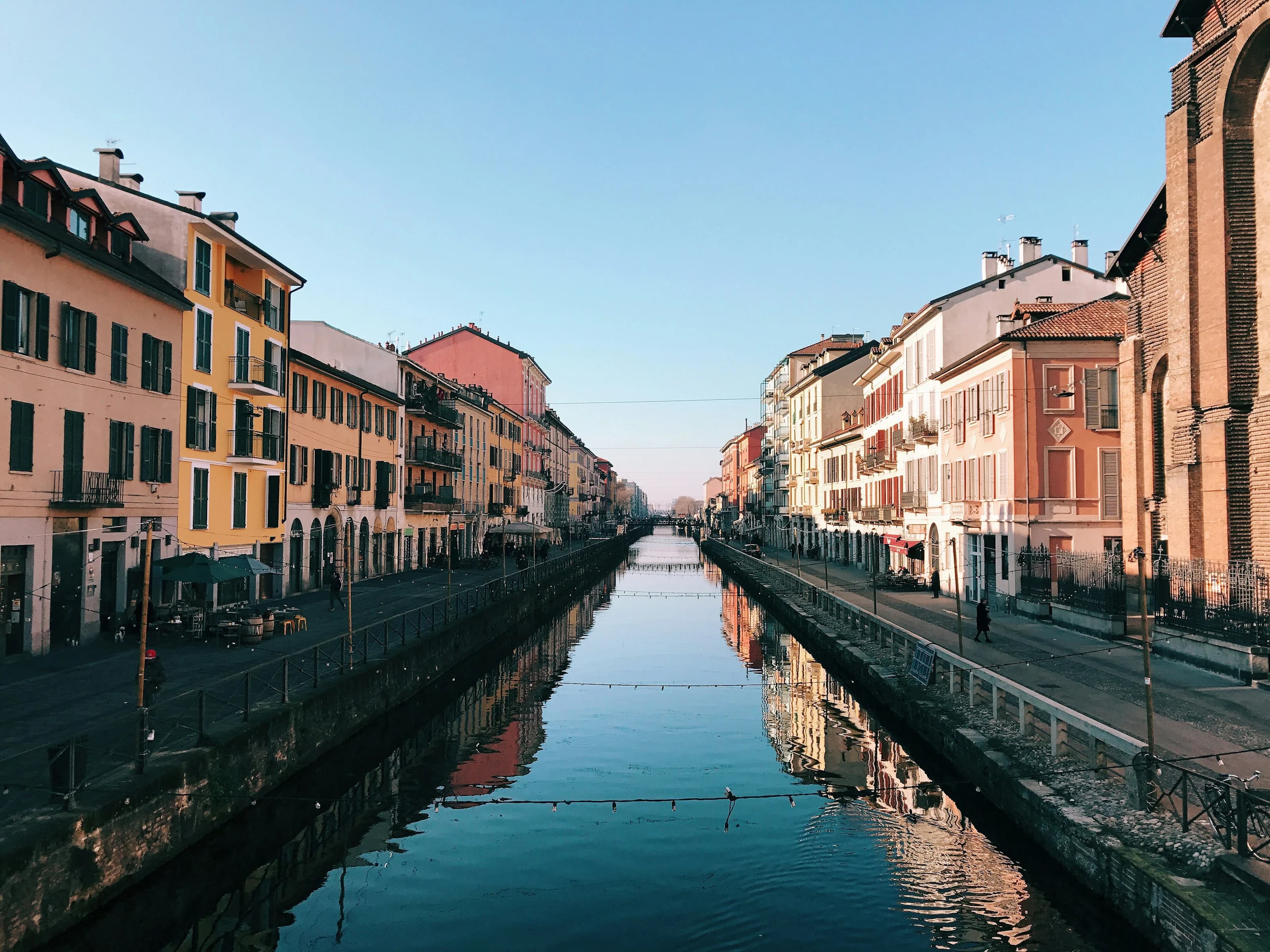 Un naviglio di Milano in una mattina limpida, con le case colorate delle due sponde riflesse nell’acqua ferma