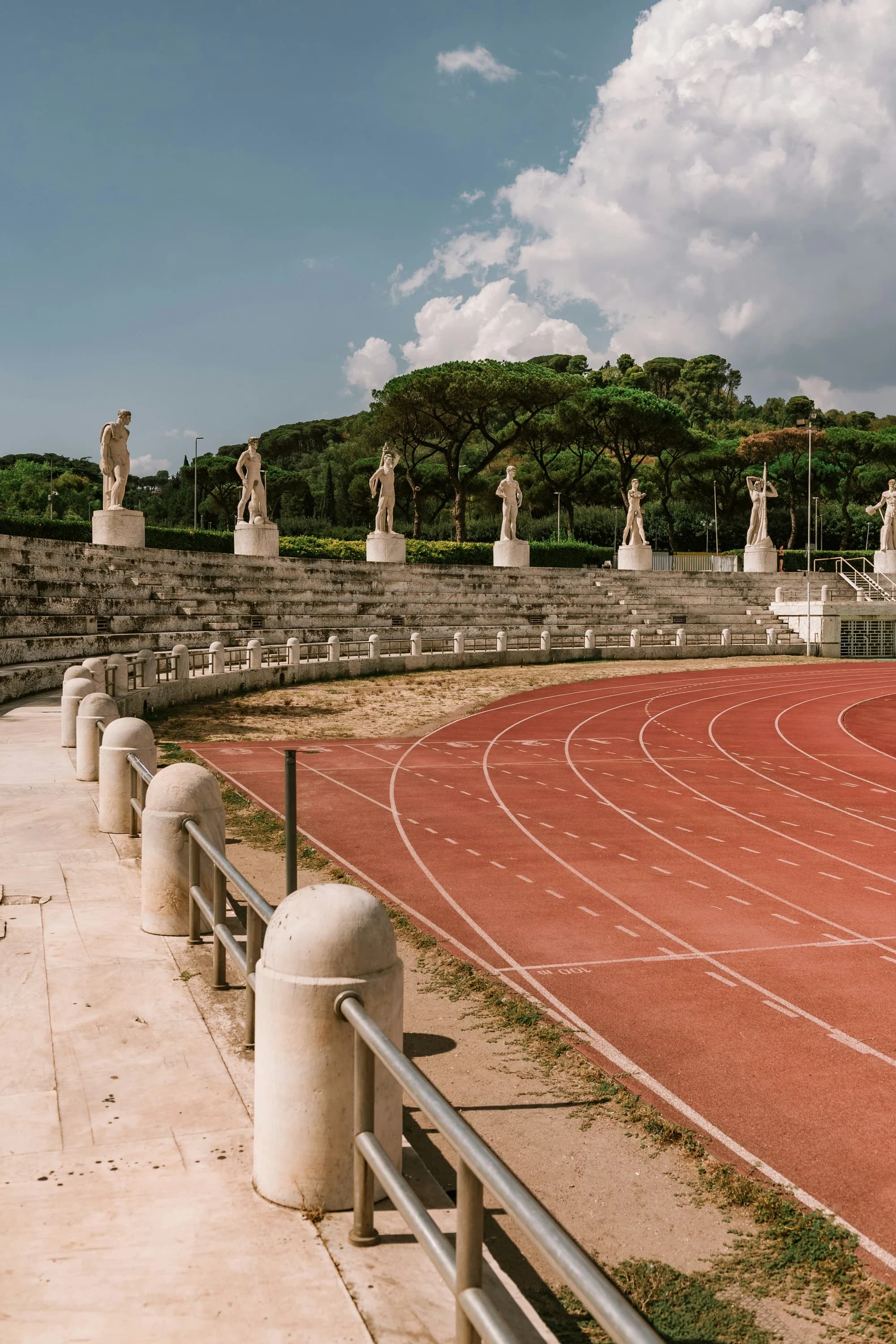 Lo Stadio dei Marmi al Foro Italico: la pista rossa, le gradinate di pietra con le statue di marmo e i pini sullo sfondo