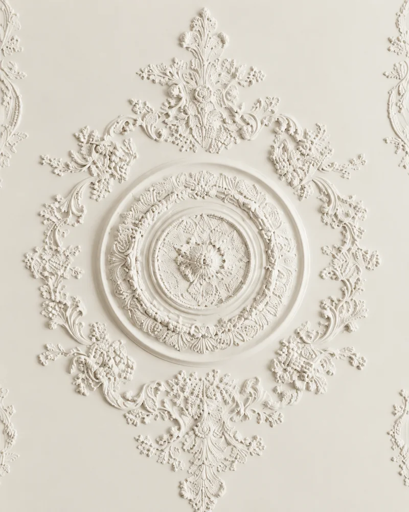 Rosone in gesso decorato al centro di un soffitto, con ghirlande e volute