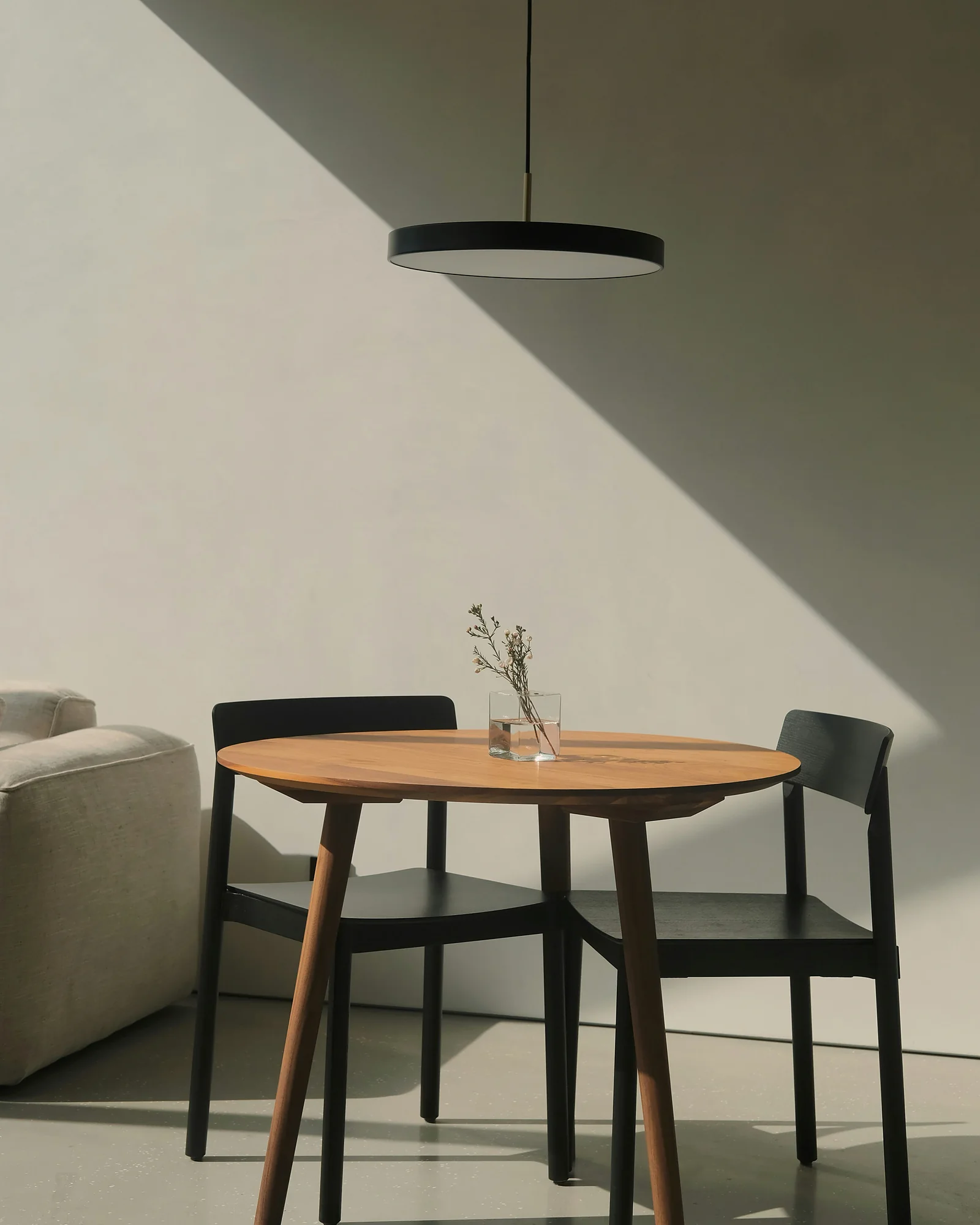 A round table with two black chairs under a sloping ceiling, beside the sofa