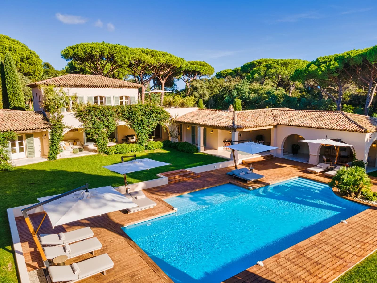 The living room at Villa Malko: white sofas, a wooden bookcase and arches opening onto the garden