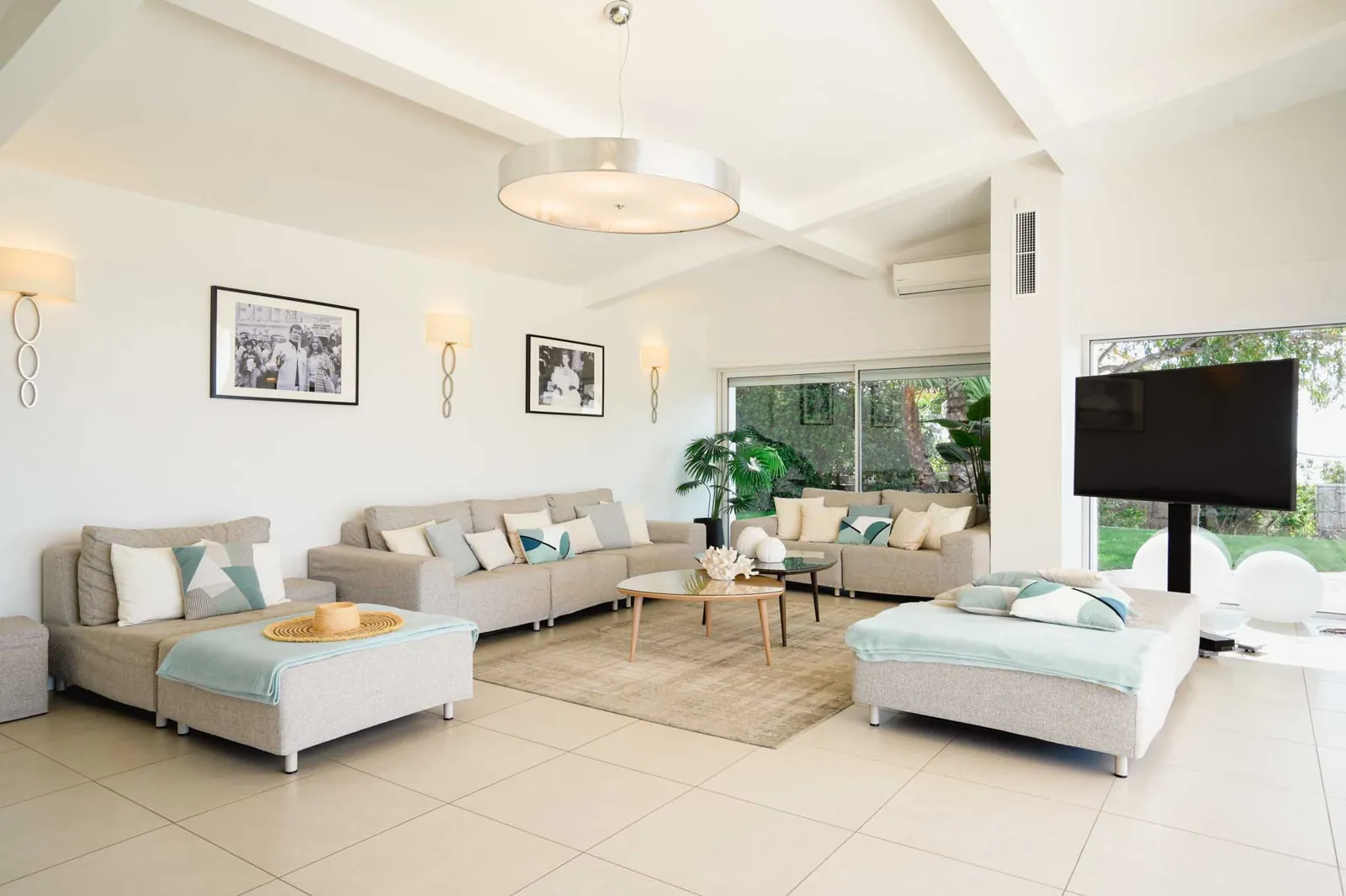 Il soggiorno di Villa Paradiso: divani chiari, il soffitto a travi bianche e le vetrate sul giardino