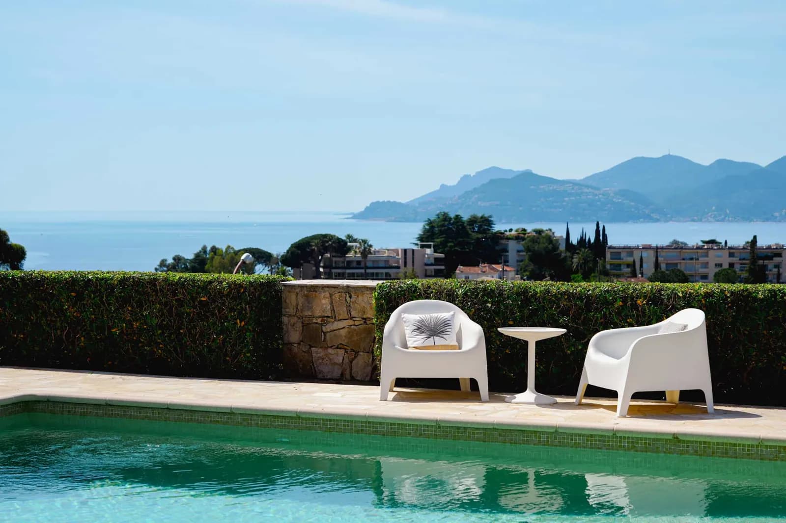 The living room at Villa Paradiso: pale sofas, a white beamed ceiling and glass doors onto the garden