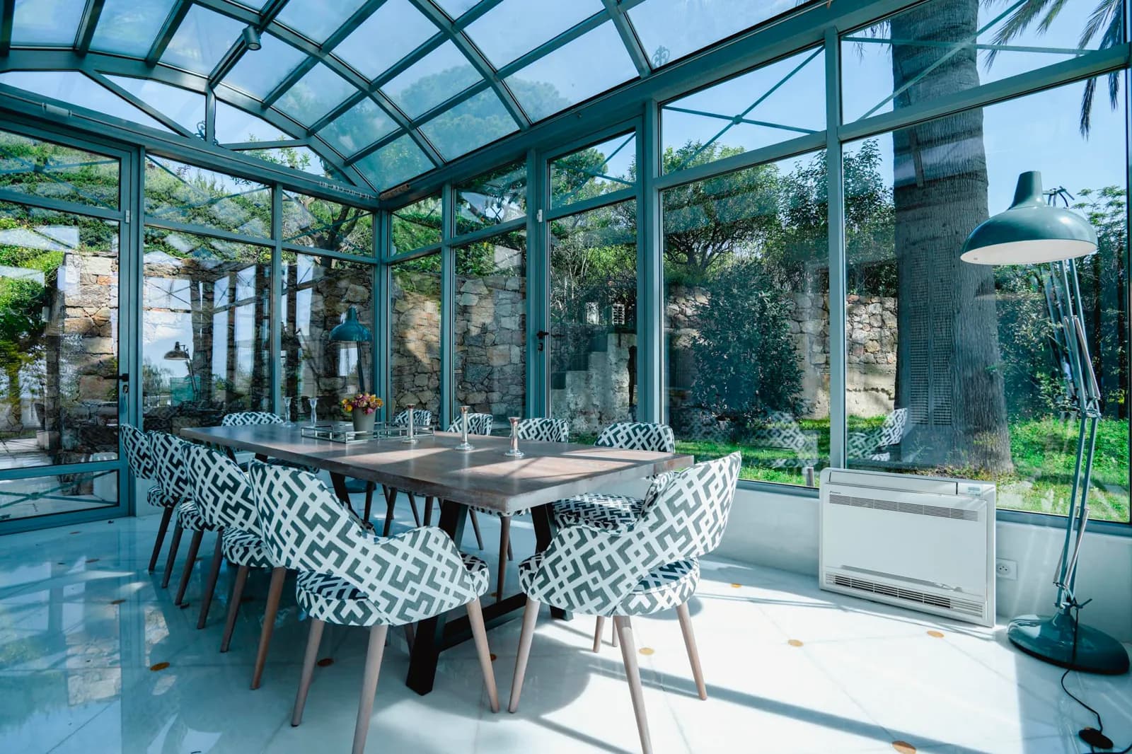 La veranda di Villa Reale: un lungo tavolo da pranzo sotto una copertura di vetro, fra le palme